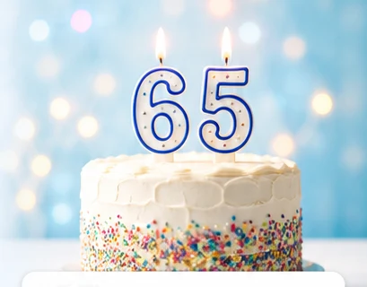 A white birthday cake with lit number 6 and 5 candles.